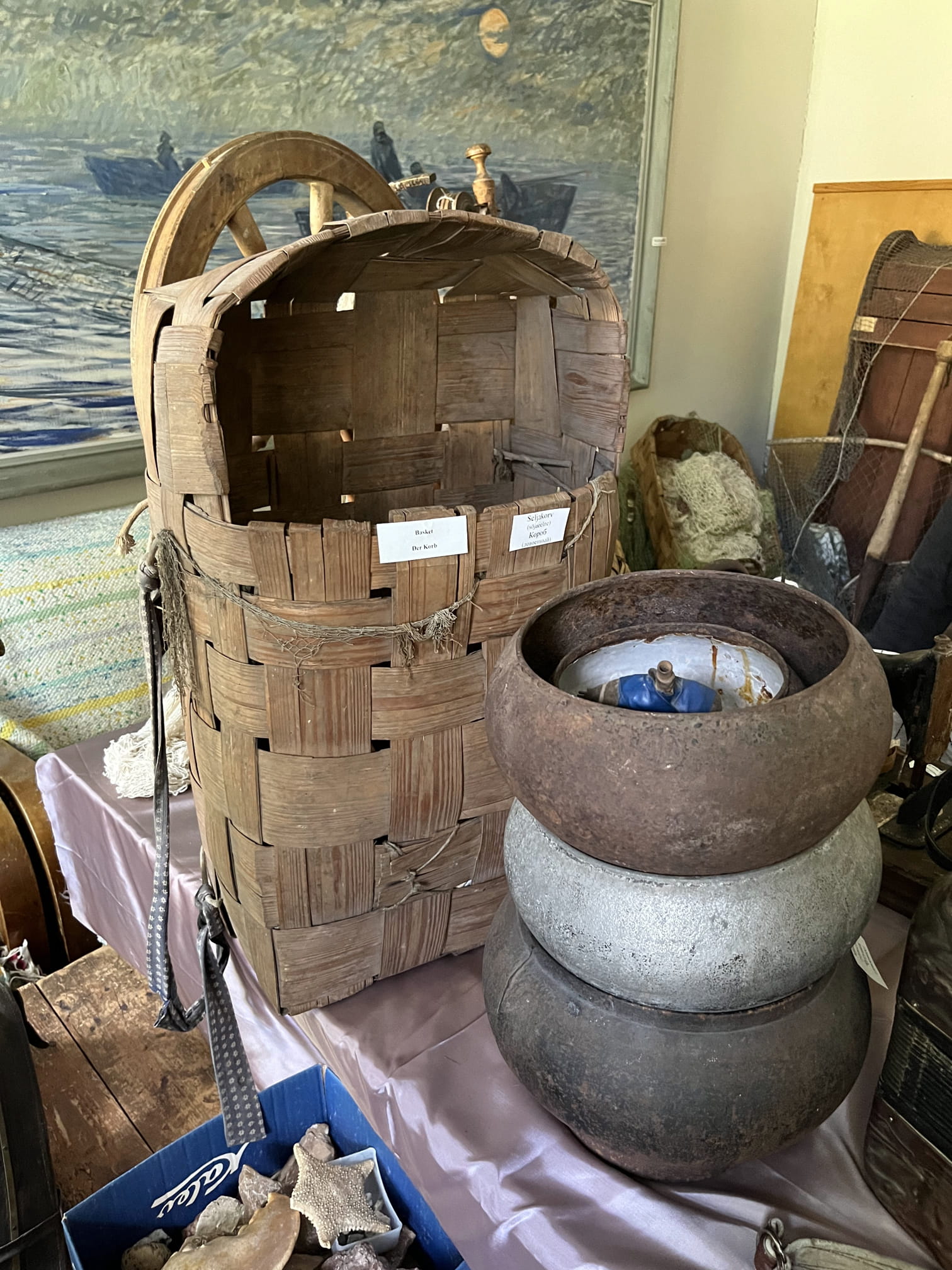 a large wooden backpack basket and several stacked metal cauldrons/basins, with an **enamel basin placed inside the top one.