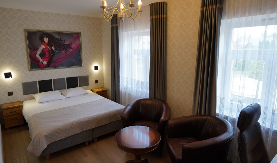 Numbritoas on telekas, laud ja kaks nahast tugitooli ning suured aknad pimendavate kardinatega