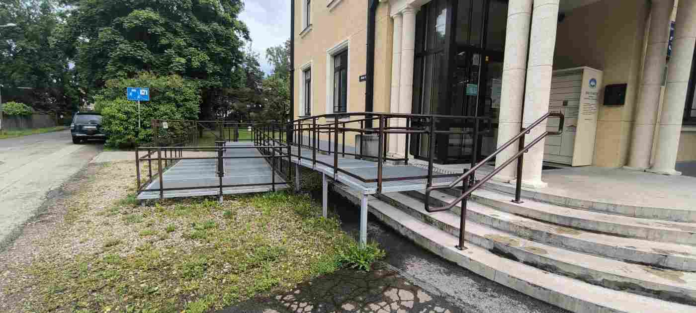 Uzbrauktuve pie dzeltenas krāsas divstāvu ēkaas