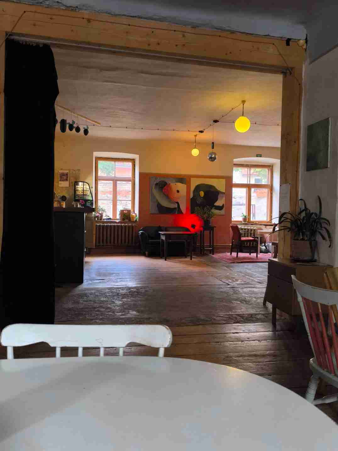 Istaba ar koka grīdu, vairākas lampas, galdi, krēsli
