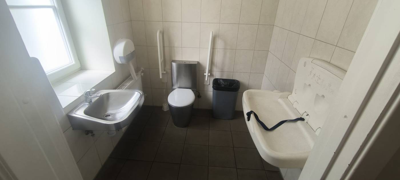 Tualetē pods, miskaste, papīra dvieļu turētājs, radiators. Dzelzs izlietne bez spoguļa un bērnu pārtināmais galdiņs
